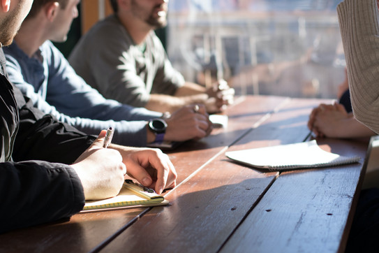 People with notepads on a wooden table